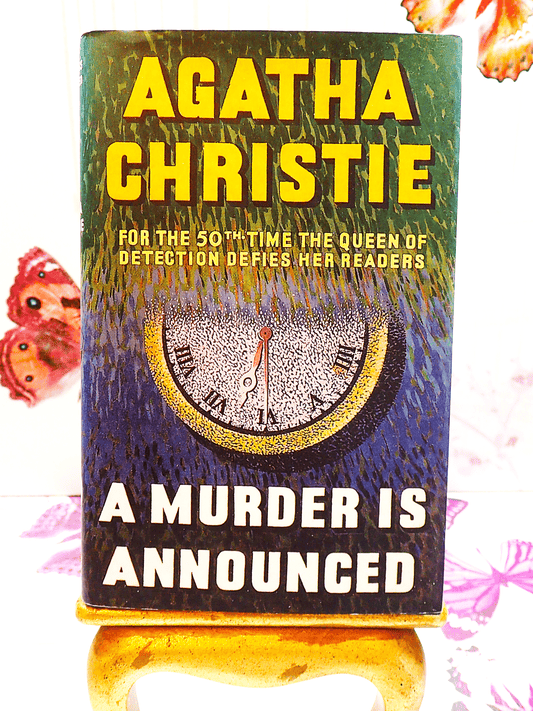 Front cover of Agatha Christie A Murder is Announced showing an image of a clock and titles in vivid yellow. 