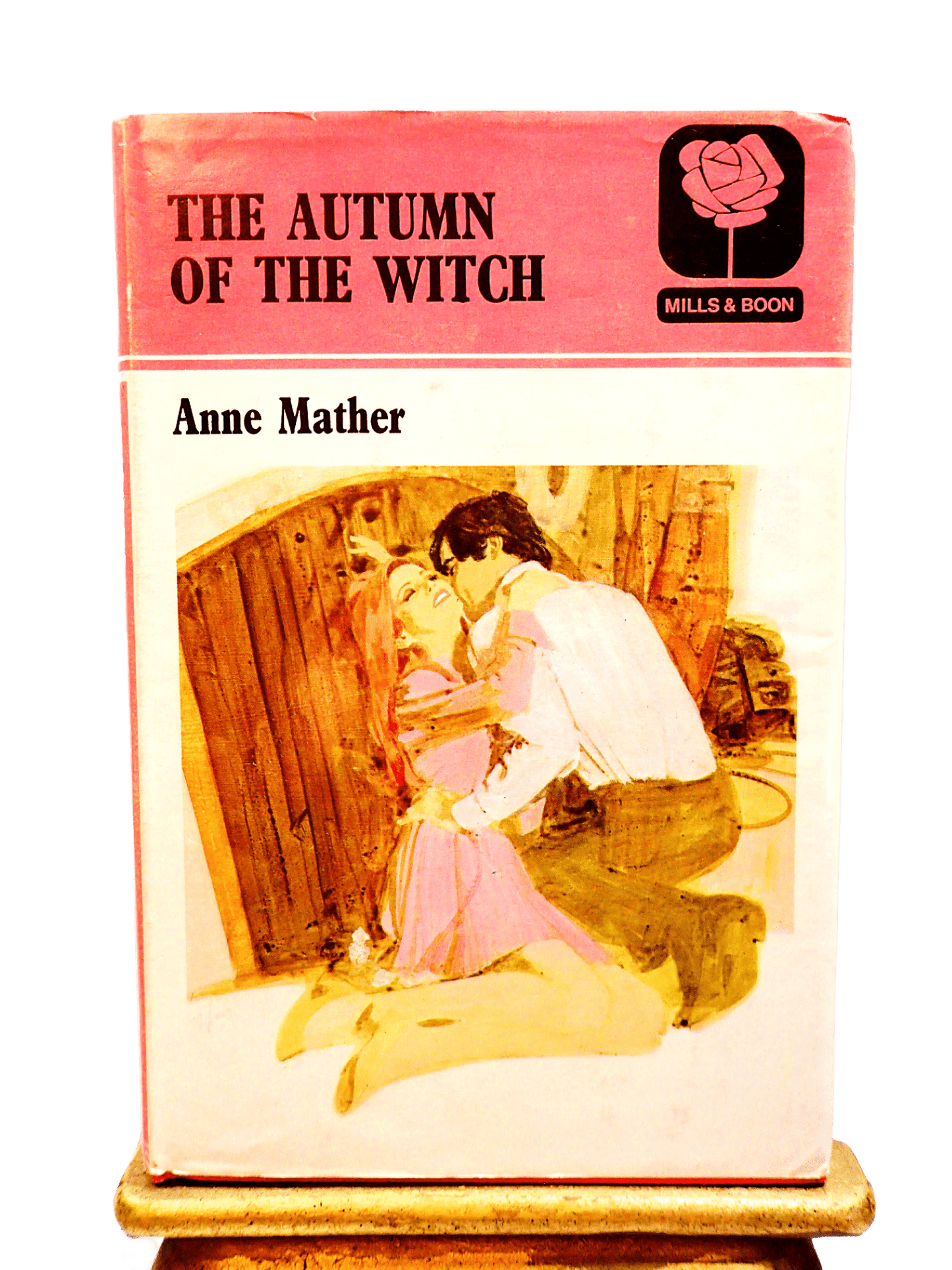Pink front cover showing a man embracing a woman of Autumn of the Witch First Edition vintage hardback Mills and Boon Book.