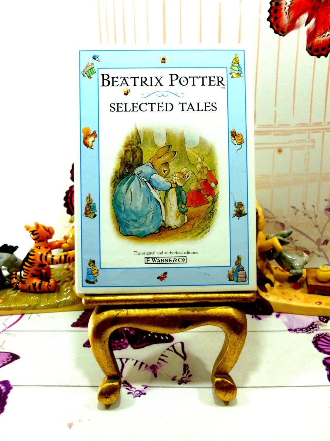 Front cover of vintage book Beatrix Potter Selected Tales showing illustration of Peter Rabbit being dressed by his mother rabbit against a blue ground with other Beatrix Potter characters.