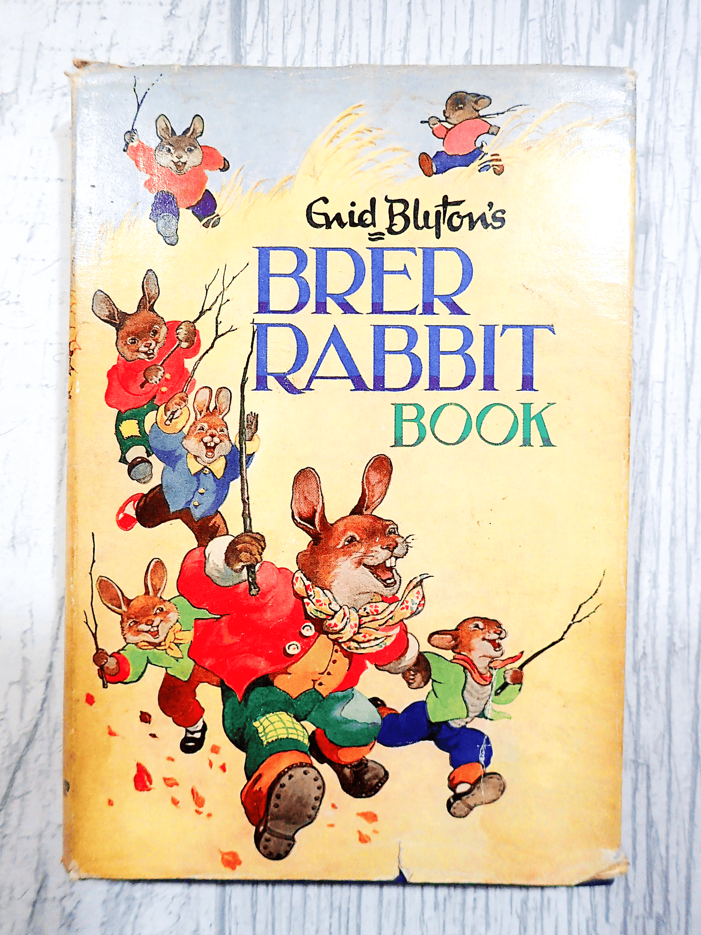 Front Cover and Spine of Enid Blyton's Brer Rabbit Book Vintage Childrens Bedtime Stories First Edition 1963 showing lots of dressed Bunnies running in a hay field against a light background.