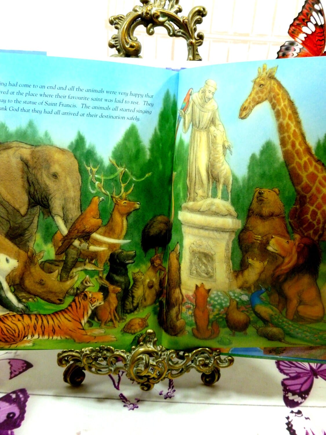 Illustration from vintage children's book Chaucer the Cat and the Animal Pilgrims showing animals sat looking at a statue of St Francis of Assisi.