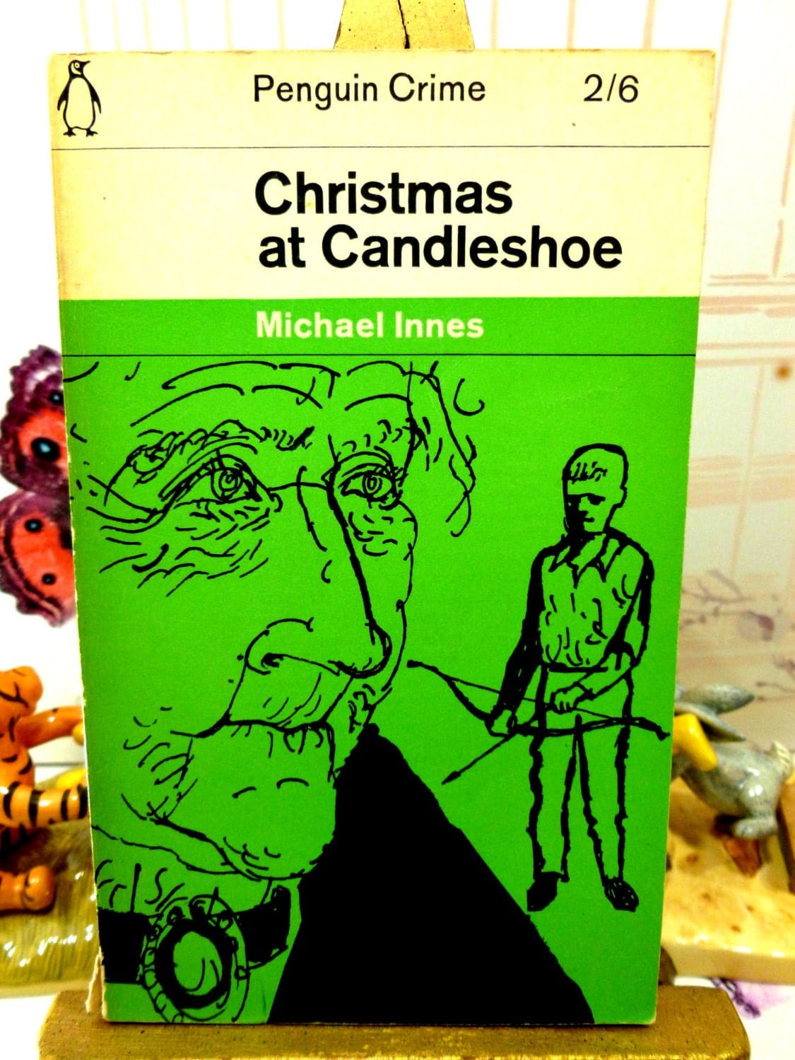 Front cover of Vintage Penguin Paperback Christmas at Candleshoe by Michael Innes First Edition showing a drawing of a man and a boy on a green ground.