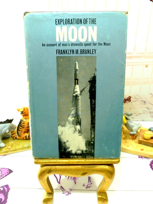 Front cover of vintage book Exploration of the Moon showing a rocket launch against a metallic blue ground. 