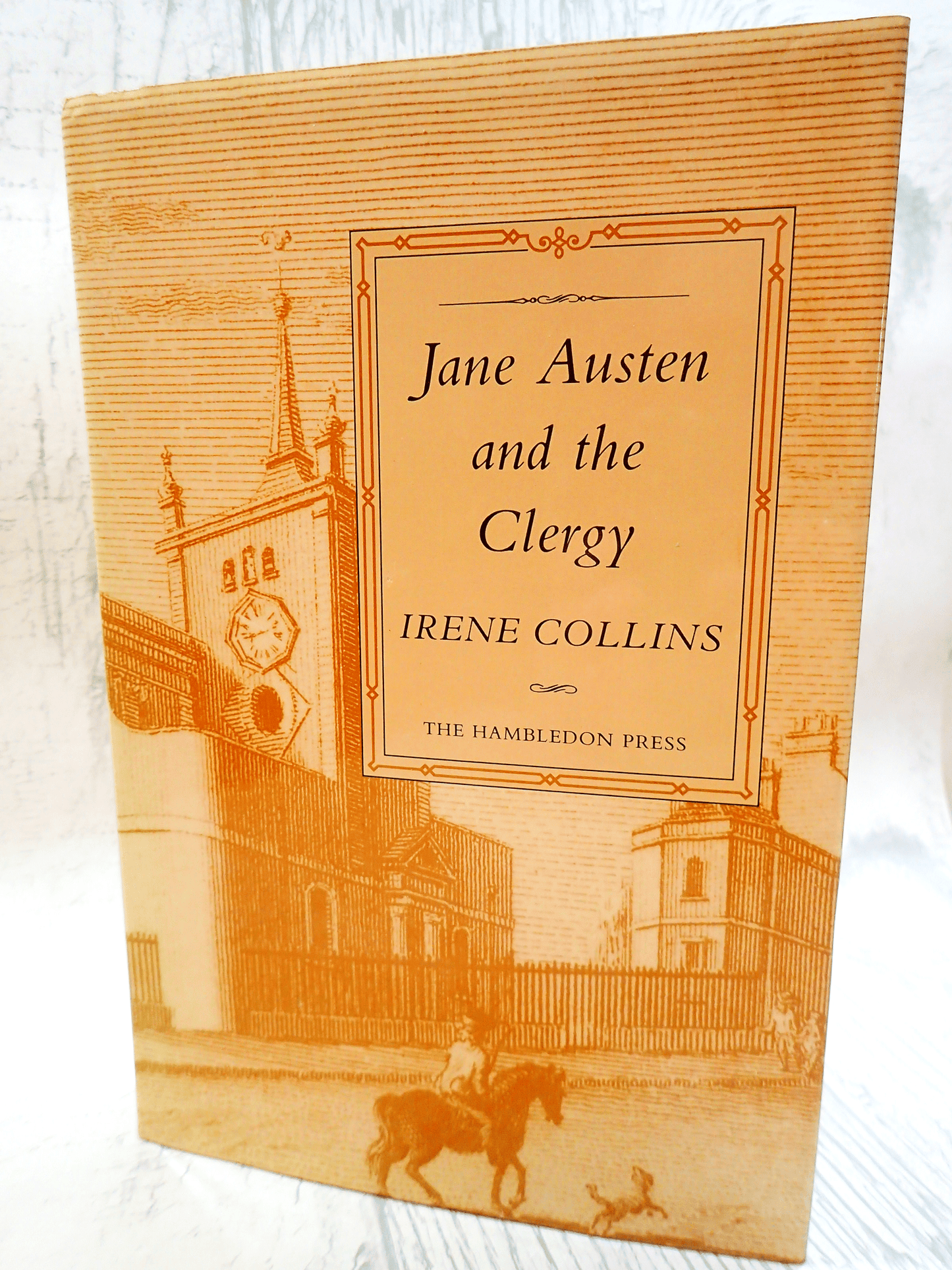 Front cover of vintage book Jane Austen and the Clergy by Irene Collins showing a sepia engraving of a Regency street against a light background.
