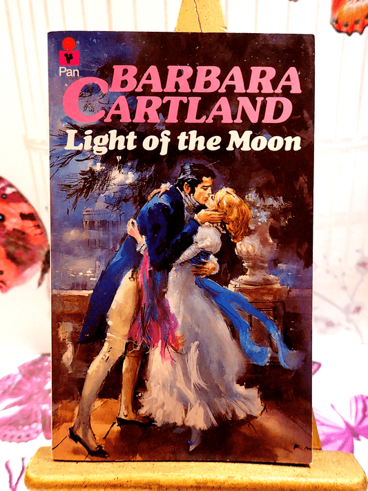 Front cover of Light of the Moon Barbara Cartland Pan Paperback First Edition showing a handsome man kissing passionately, a woman in a long white dress. 