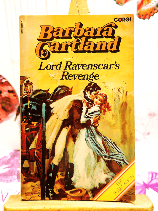 Front cover of Lord Ravenscar's Revenge Barbara Cartland Corgi Paperback showing a handsome man in a cape kissing a lady in 19th century dress. 