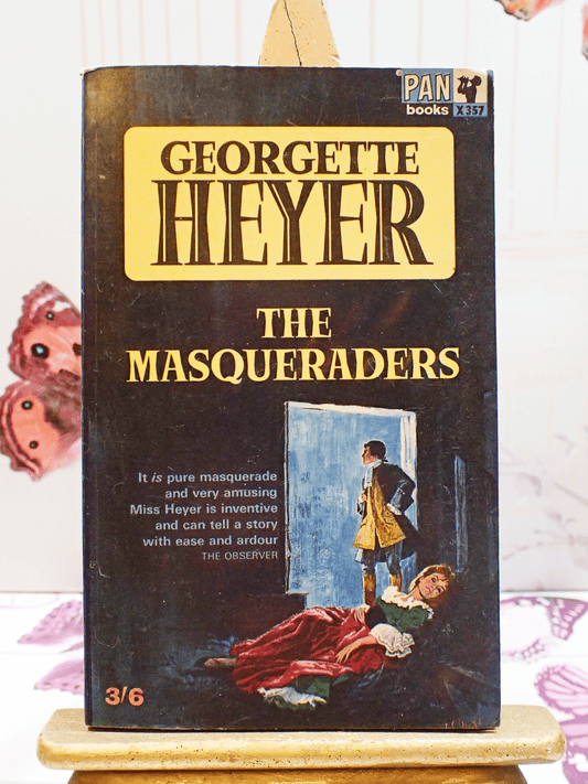 Front cover of vintage Pan paperback book, 'The Masqueraders', by Georgette Heyer showing a man and woman in Georgian costume and the book titles in yellow and black.