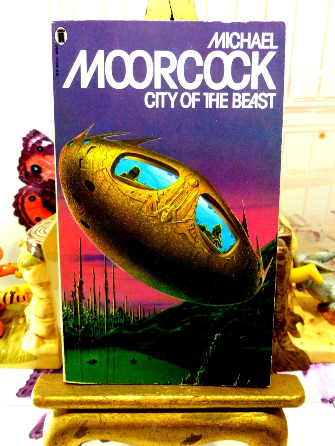 Front cover of Michael Moorcock Vintage Sci Fi Paperback Book 1970s City of the Beast Warriors of Mars Martian Trilogy showing weird spaceship with bug eye windows.