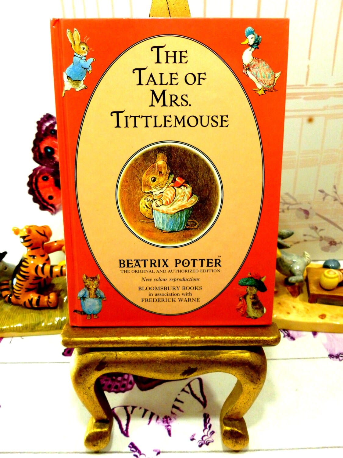 Front cover of The Tale of Mrs TittleMouse First Edition Bloomsbury Book 1993 Beatrix Potter with Beatrix Potter characters against a red ground.