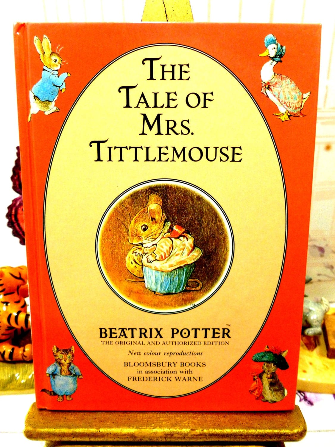 Front cover of The Tale of Mrs TittleMouse First Edition Bloomsbury Book 1993 Beatrix Potter with Beatrix Potter characters against a red ground.