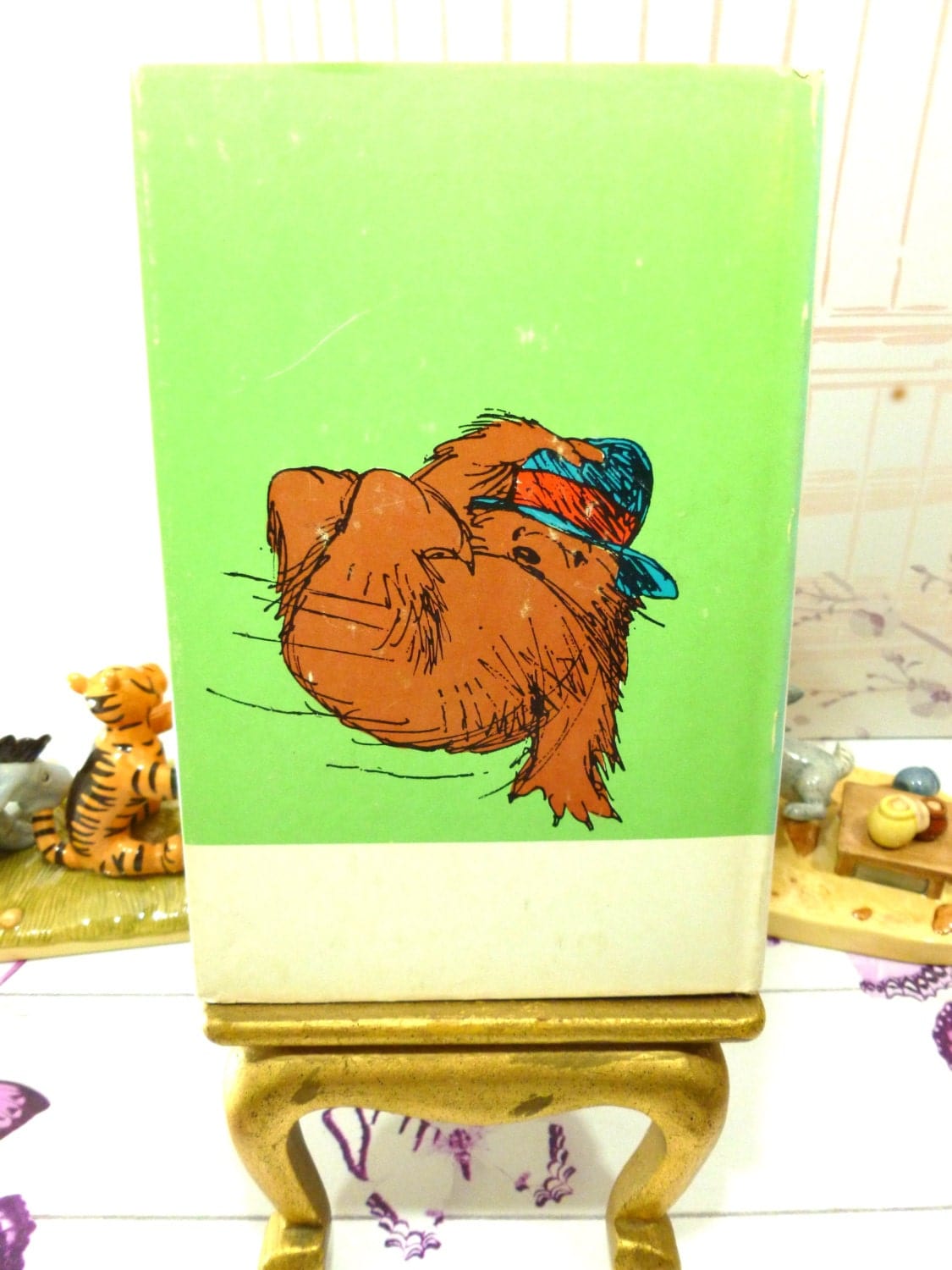 Back cover of Paddington Takes the Air Vintage Book First American Edition with Dust Jacket showing Paddington Bear wearing a hat against a green ground.