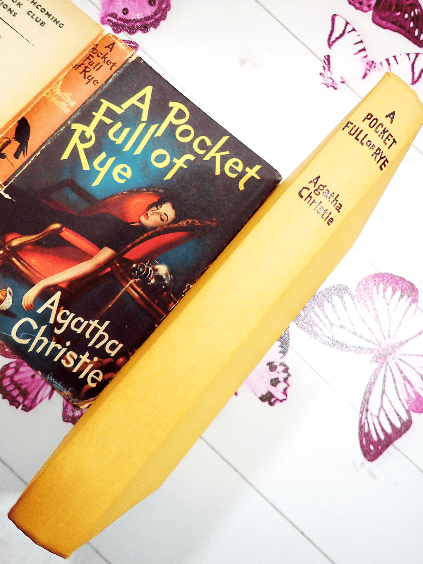 Spine of A Pocketful of Rye Agatha Christie Vintage Thriller Book Club First Edition 1954, showing black titles on the yellow boards with the Dust Jacket behind.