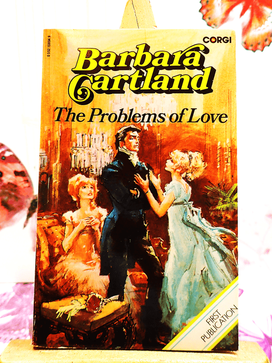 Front cover of The Problems of Love Barbara Cartland Corgi first edition showing a pretty woman in a blue dress pleading with a handsome man.