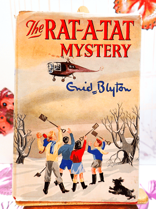 Front cover of The Rat-A-Tat Mystery by Enid Blyton Vintage Children's Book Collins First Edition 2nd Imp. showing children in a snowy field with a dog and a helicopter