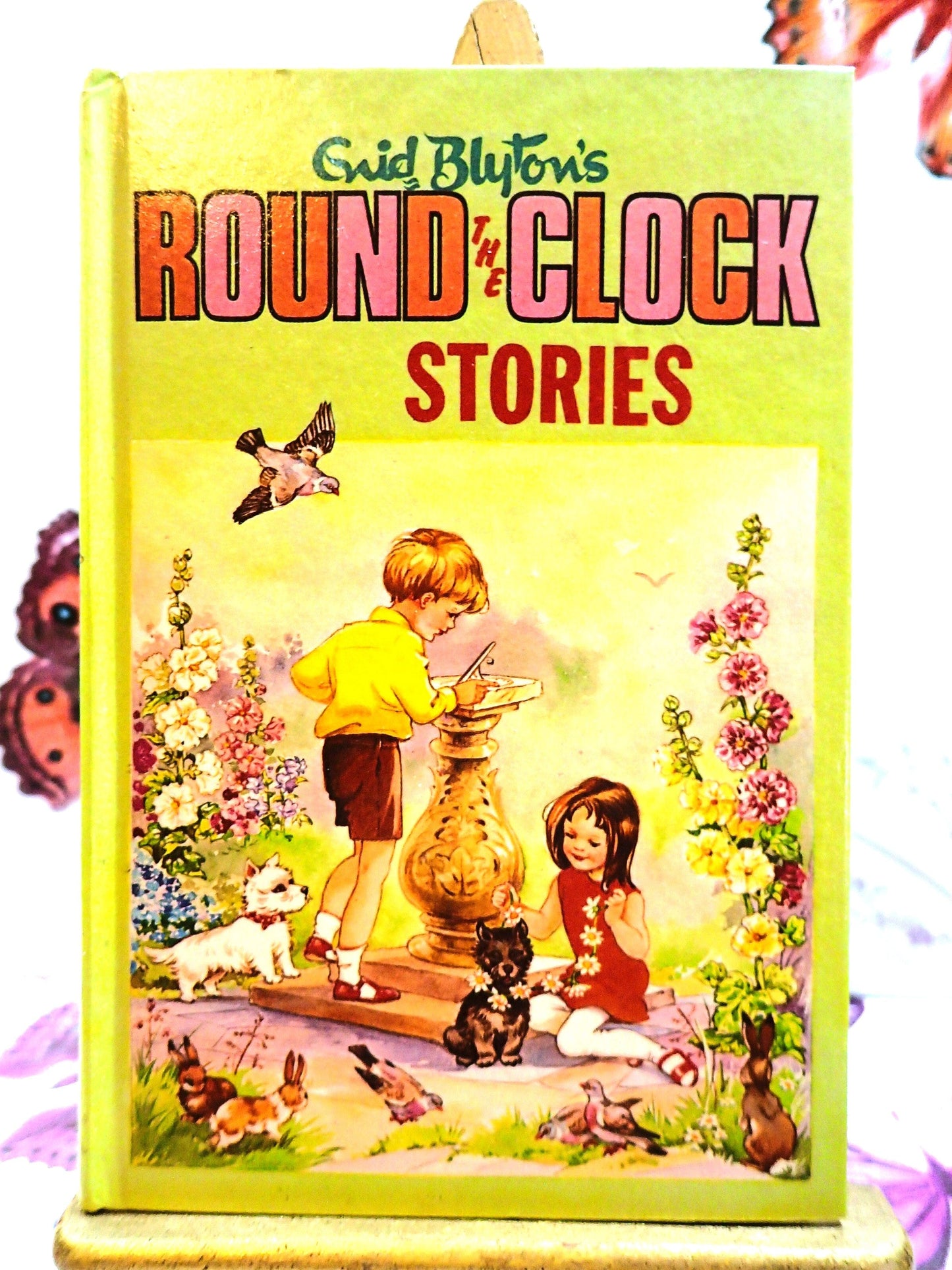 Front cover of Enid Blyton's Round the Clock Stories Vintage Children's Book 1970's Bedtime Fairytales showing children and dogs playing round a sundial.