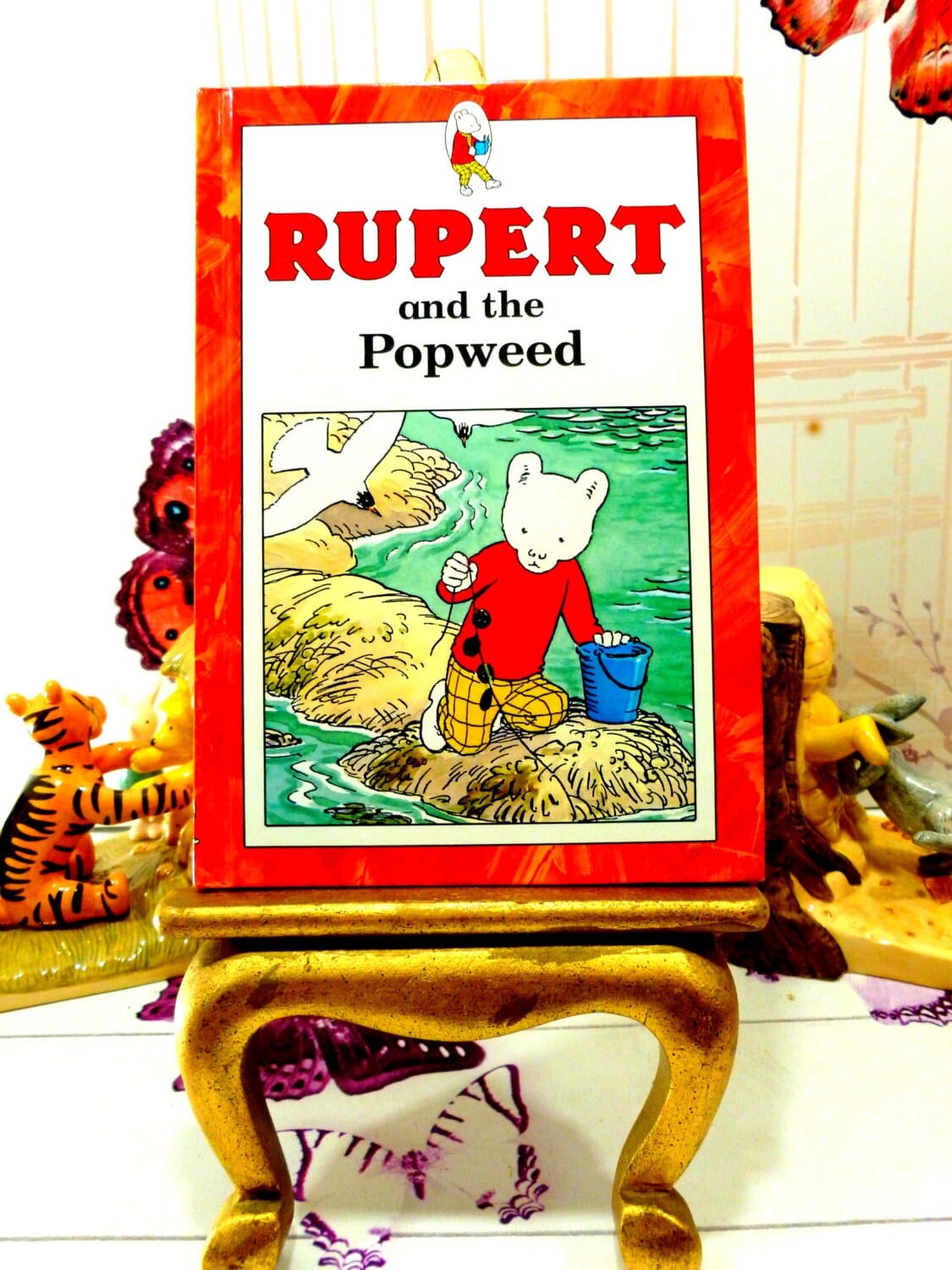 Front cover of Rupert and the Popweed Vintage Hardback Rupert Book 1st Ed 1991 showing Rupert and a Seagull against a red border.