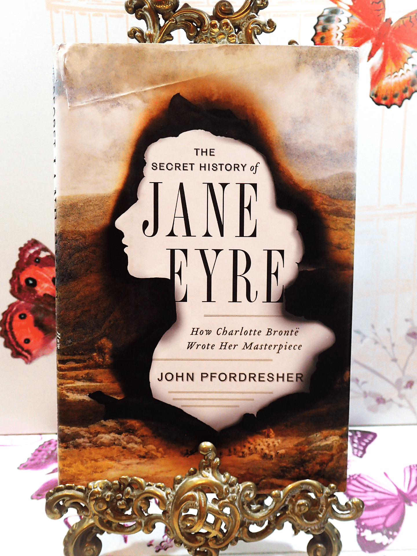 Front cover of The Secret History of Jane Eyre John Pfordresher Vintage Hardback First Edition showing silhouette of Jane Eyre burnt over image of moorland.