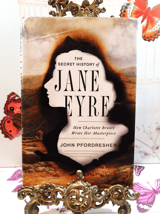 Front cover of The Secret History of Jane Eyre John Pfordresher Vintage Hardback First Edition showing silhouette of Jane Eyre burnt over image of moorland. 