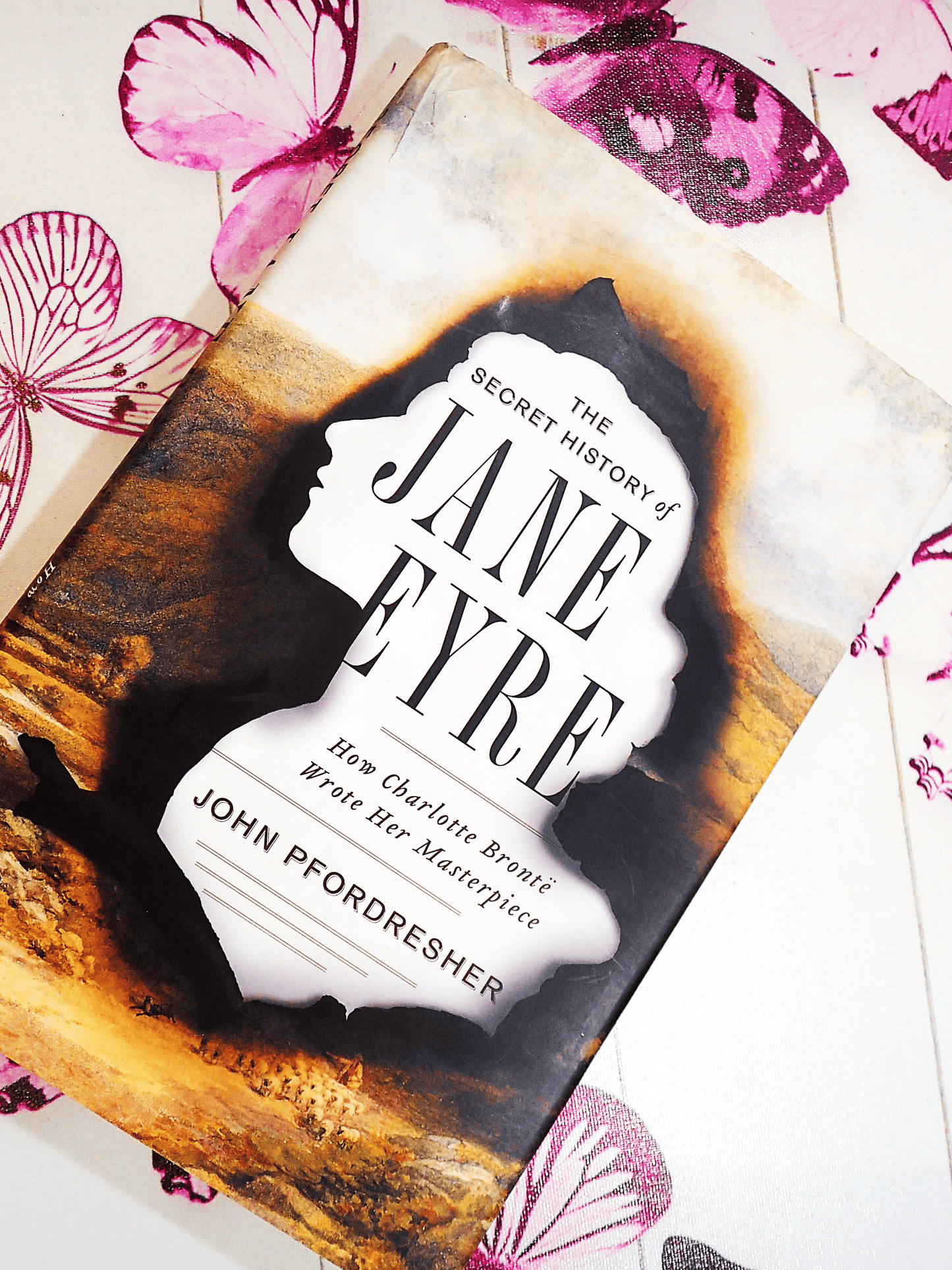 Front cover of The Secret History of Jane Eyre John Pfordresher Vintage Hardback First Edition showing silhouette of Jane Eyre burnt over image of moorland.