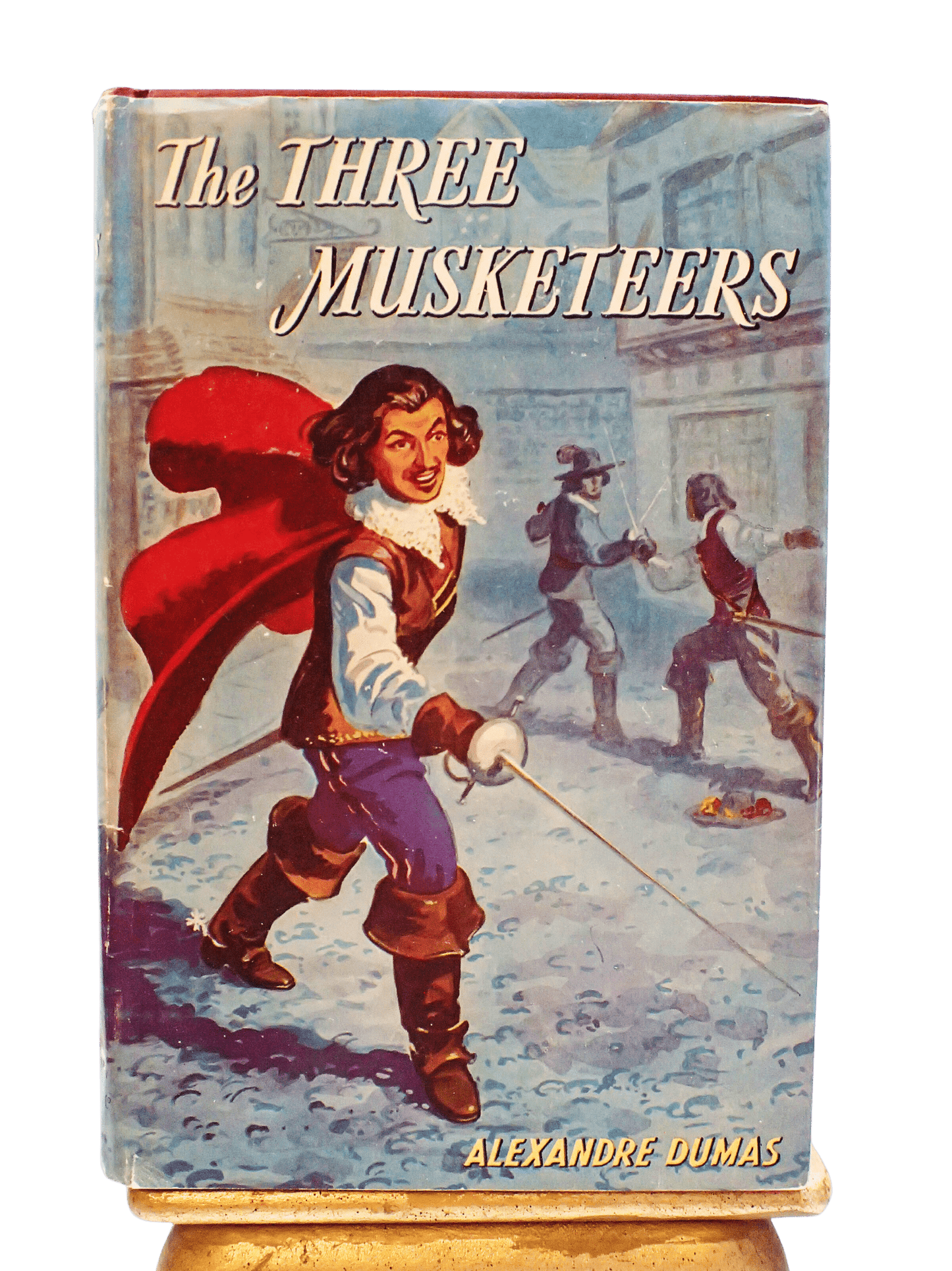 The Front cover of the Three Musketeers by Baroness Orczy vintage book showing a dashing D'artagnan holding a sword.