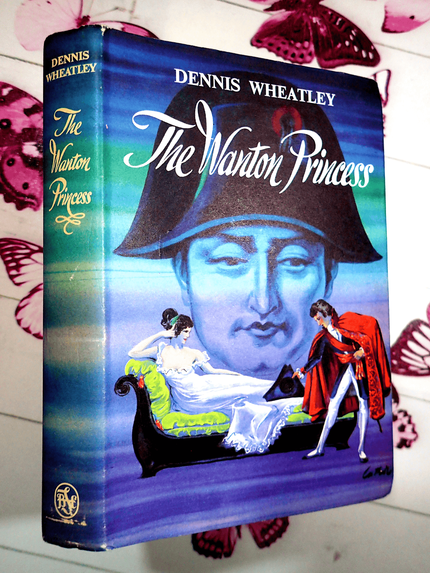Front cover of The Wanton Princess Dennis Wheatley first edition thus, showing a looming image of Napoleon and the hero Roger Brook bowing to a lady on a chaise longue.