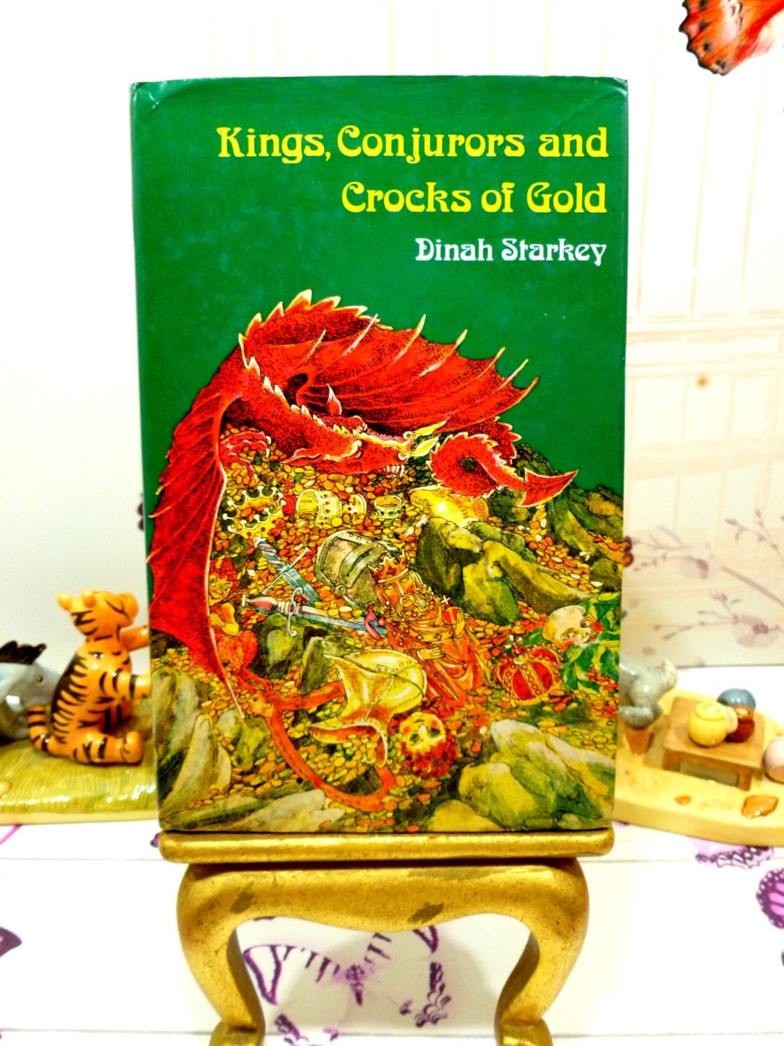 Front cover of Kings Conjurors and Crocks of Gold 1975 folk tale book with colourful dragon on its hoard against a green ground.
