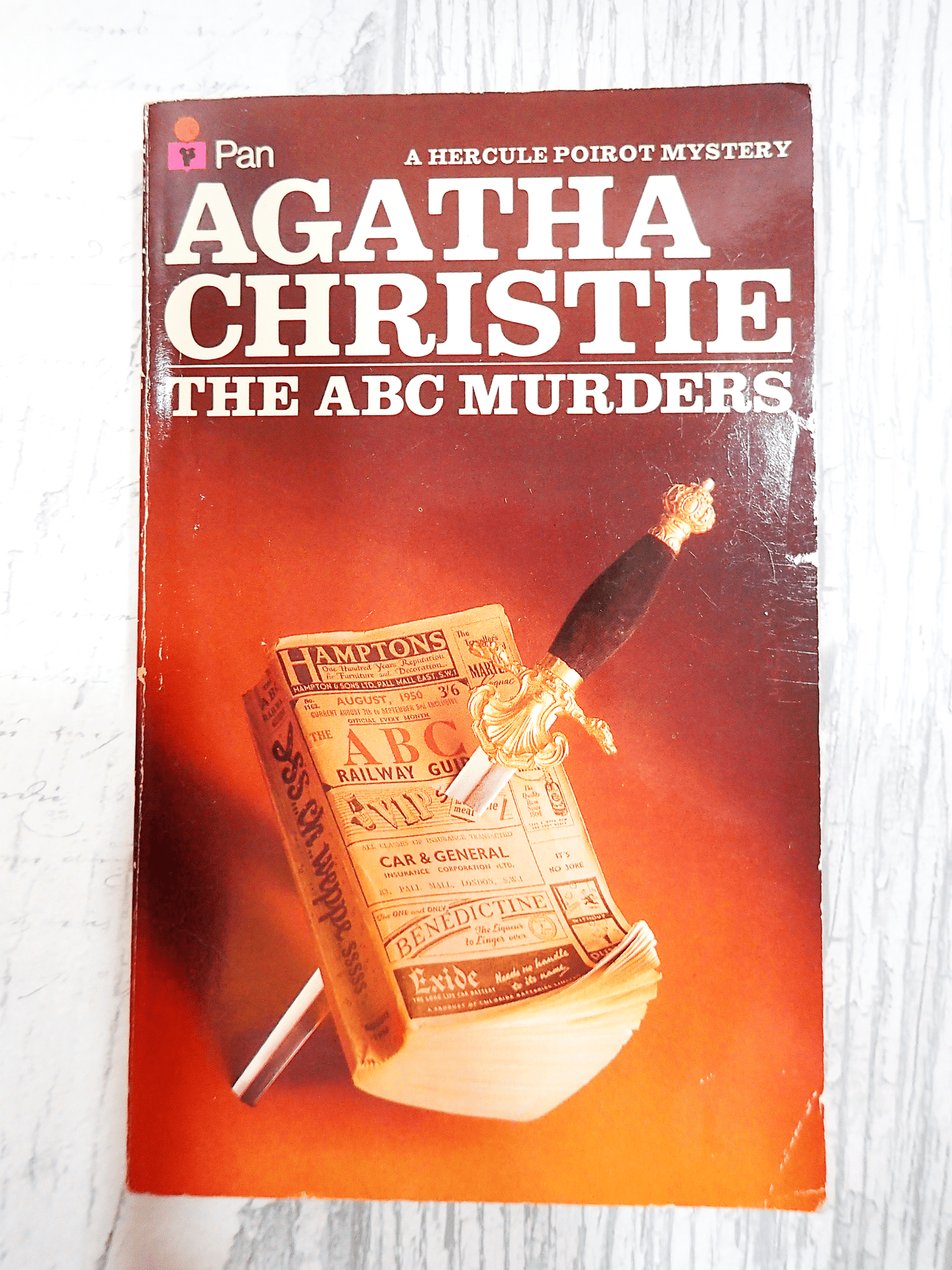 Front Cover of Agatha Christie The ABC Murders, Vintage Pan Paperback Book. Classic Crime Fiction. Showing an ABC Railway guide with a dagger through it against a blood red against a light coloured background.