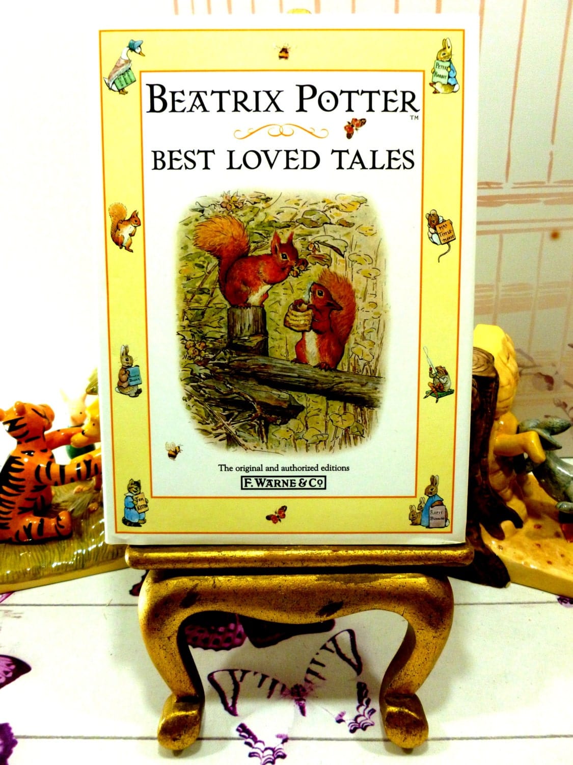 Front cover of Beatrix Potter Best Loved Tales showing Squirrel Nutkin and a squirrel holding a basket against a yellow ground illustrated with other Beatrix Potter Characters. 