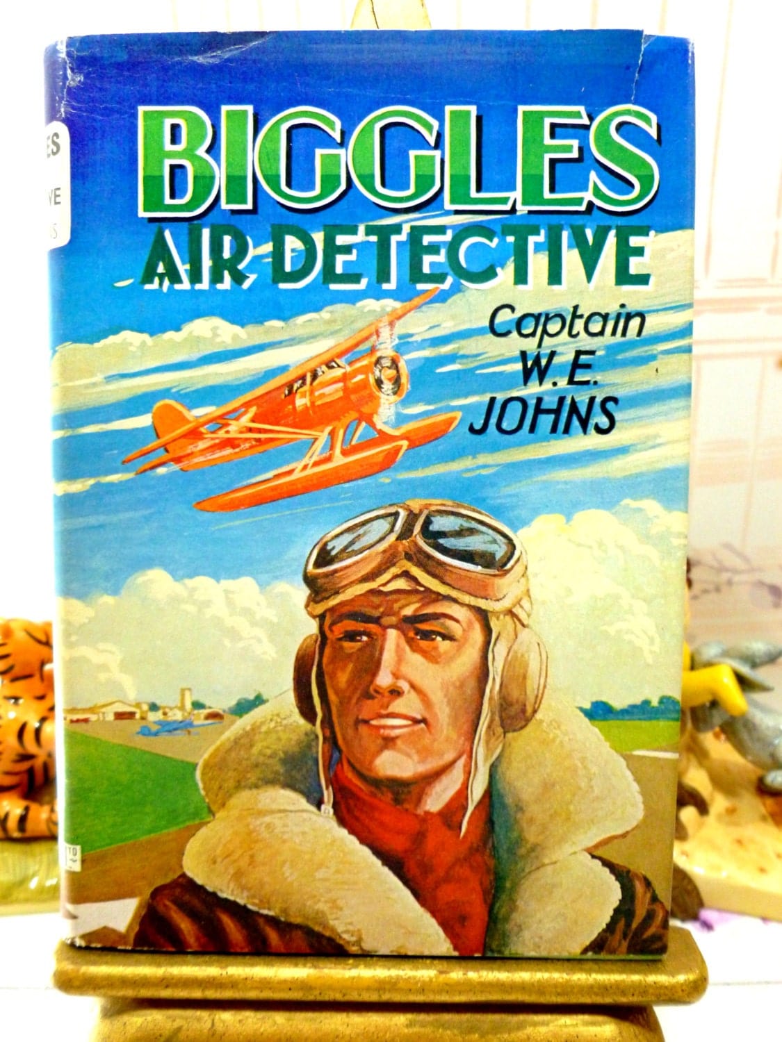 Front Cover of Biggles Air Detective Captain W.E. Johns showing Captain Biggles in Flying Uniform with goggles and an aeroplane in the background. 