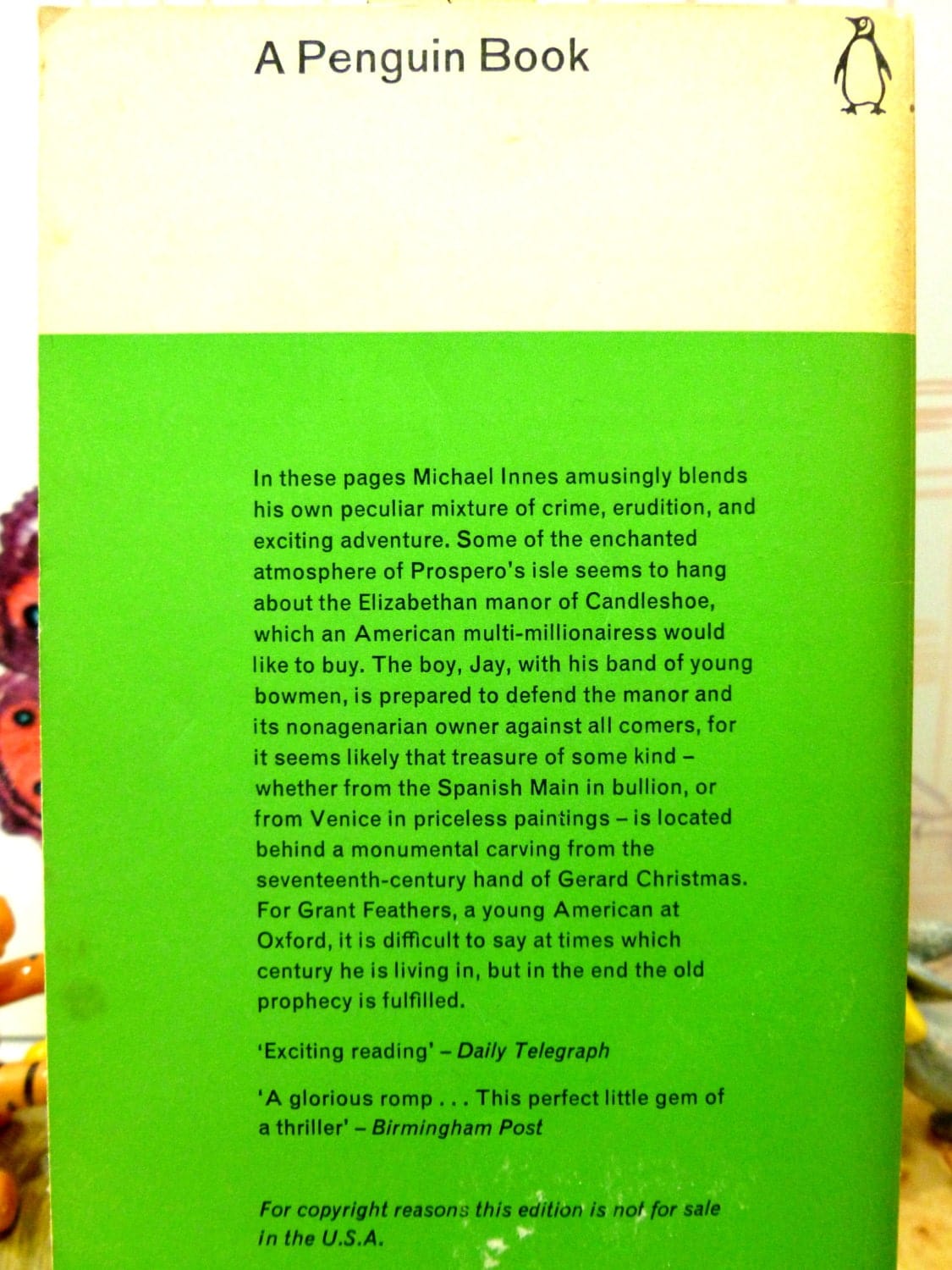 Back cover of Vintage Penguin Paperback Christmas at Candleshoe by Michael Innes First Edition showing blurb on a green ground. 