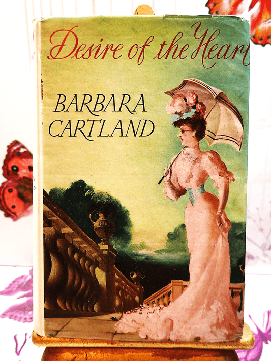 Front cover of Desire of the Heart Barbara Cartland Hardback showing a lady dressed in pink holding a pasrasol. 