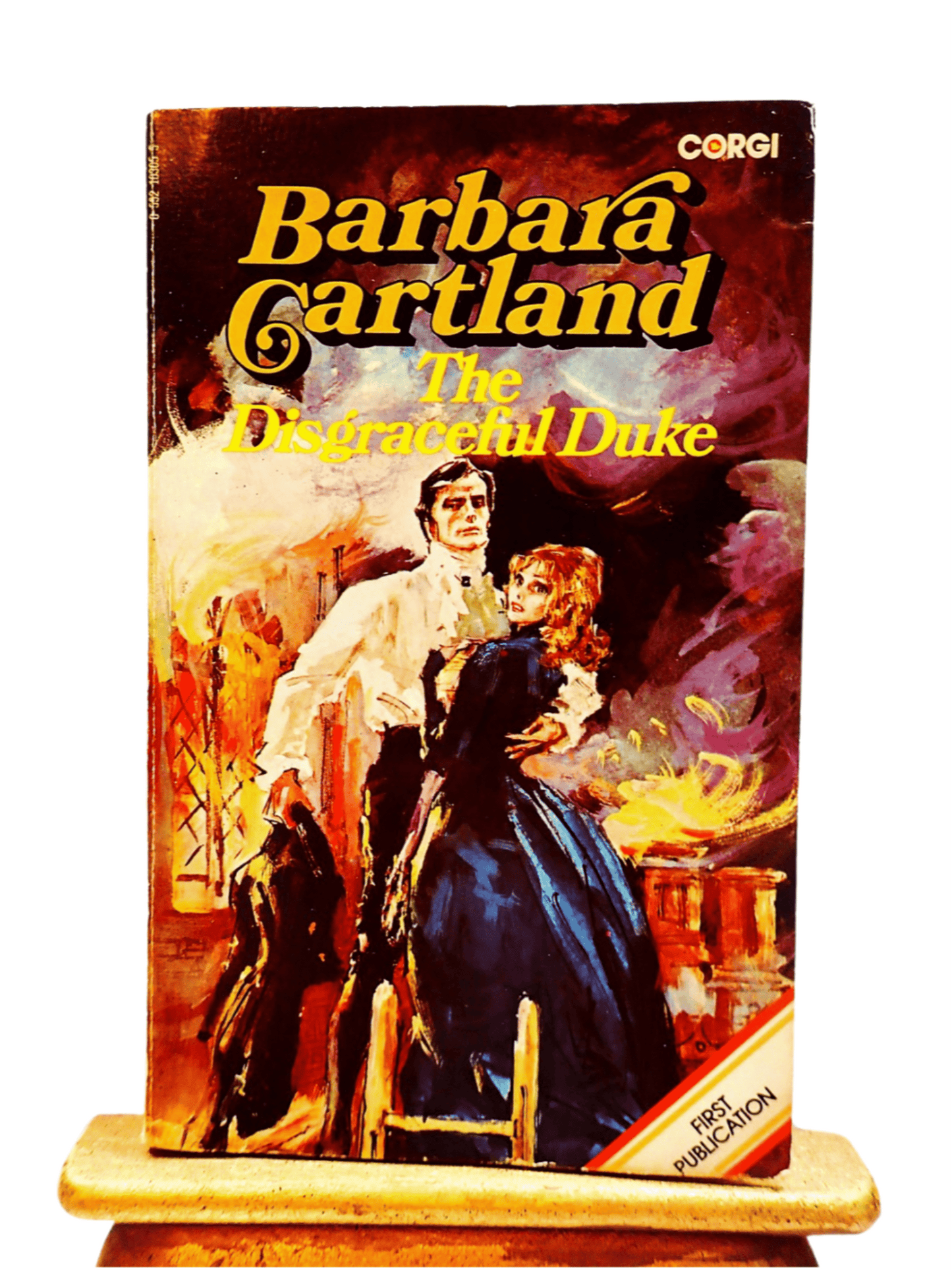 Front cover of The Disgraceful Duke Barbara Cartland Corgi Paperback showing a rakish man embracing a lady in long blue dress against a raging fire.