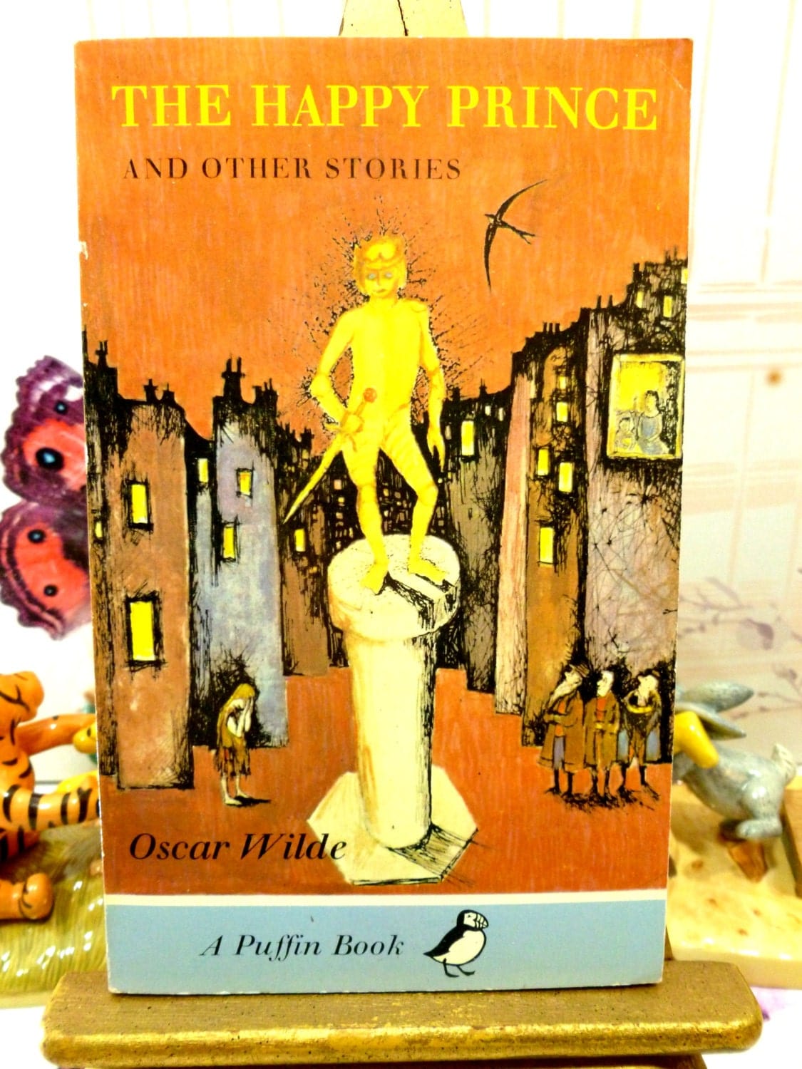 Front cover of The Happy Prince and other Stories Classic Childrens Book Vintage Puffin Book Paperback 1970s showing the golden statue of the prince and the swallow.