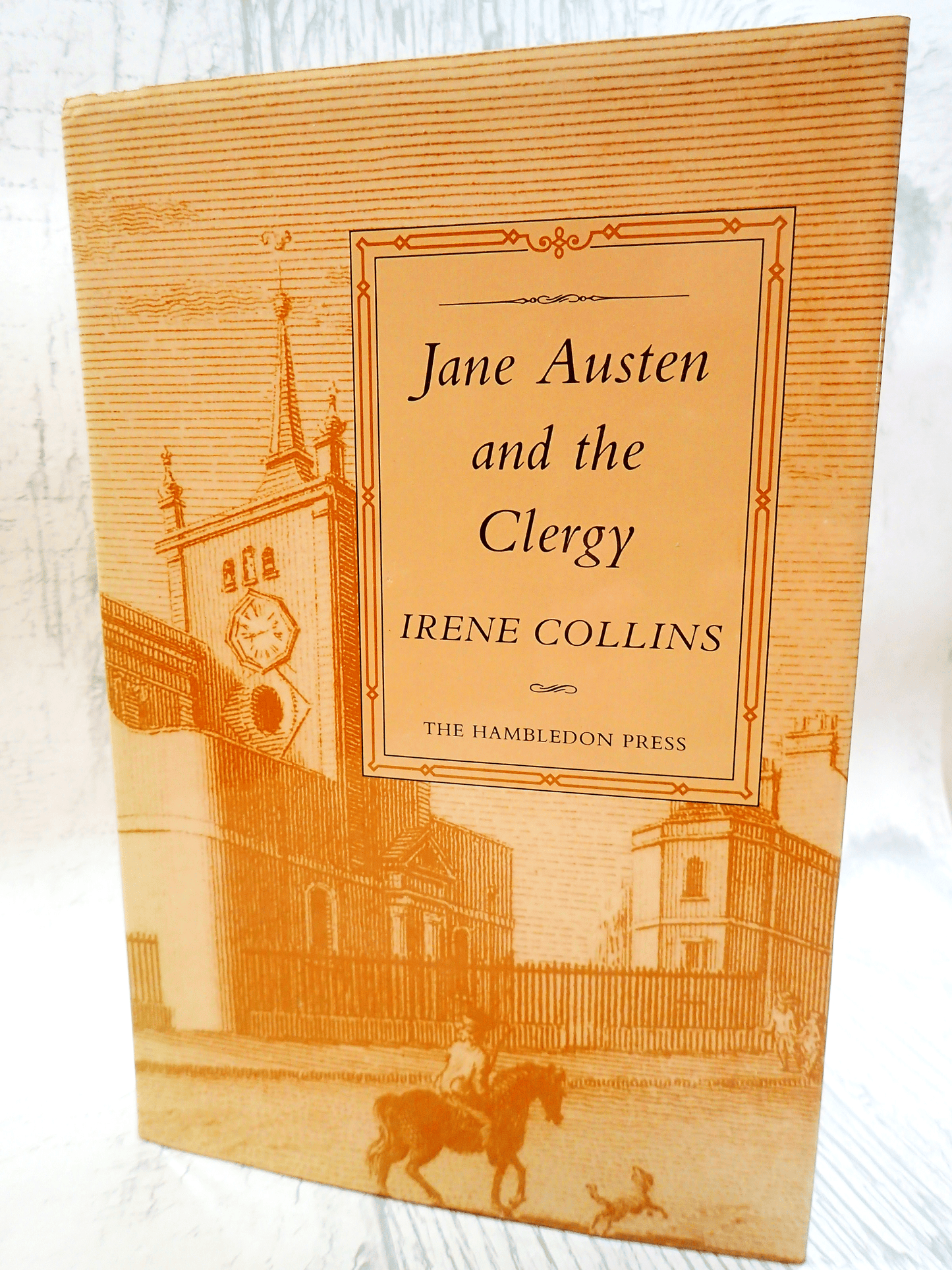 Front cover of vintage book Jane Austen and the Clergy by Irene Collins showing a sepia engraving of a Regency street against a light background. 
