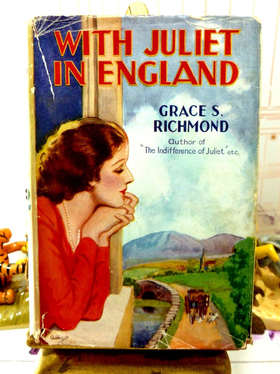 Front cover of With Juliet in England by Grace S Richmond Scarce Vintage 1930s Romance Novel showing a pensive woman looking out of a window.