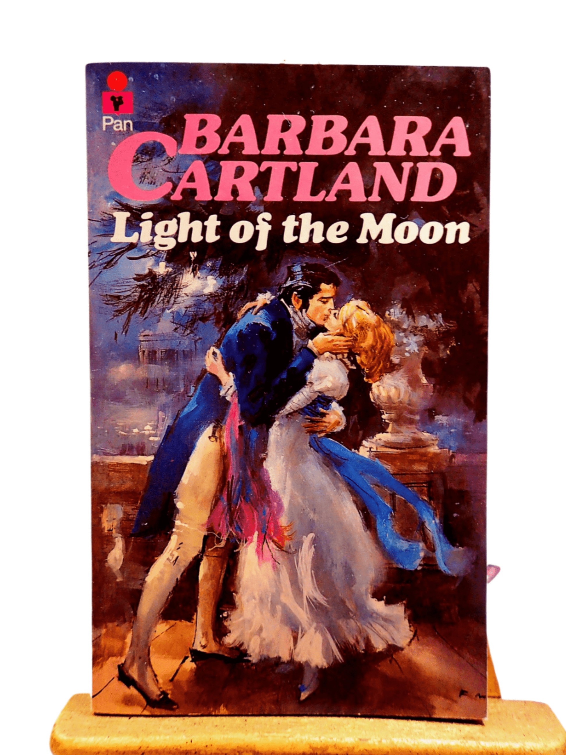 Front cover of Light of the Moon Barbara Cartland Pan Paperback First Edition showing a handsome man kissing passionately, a woman in a long white dress. 