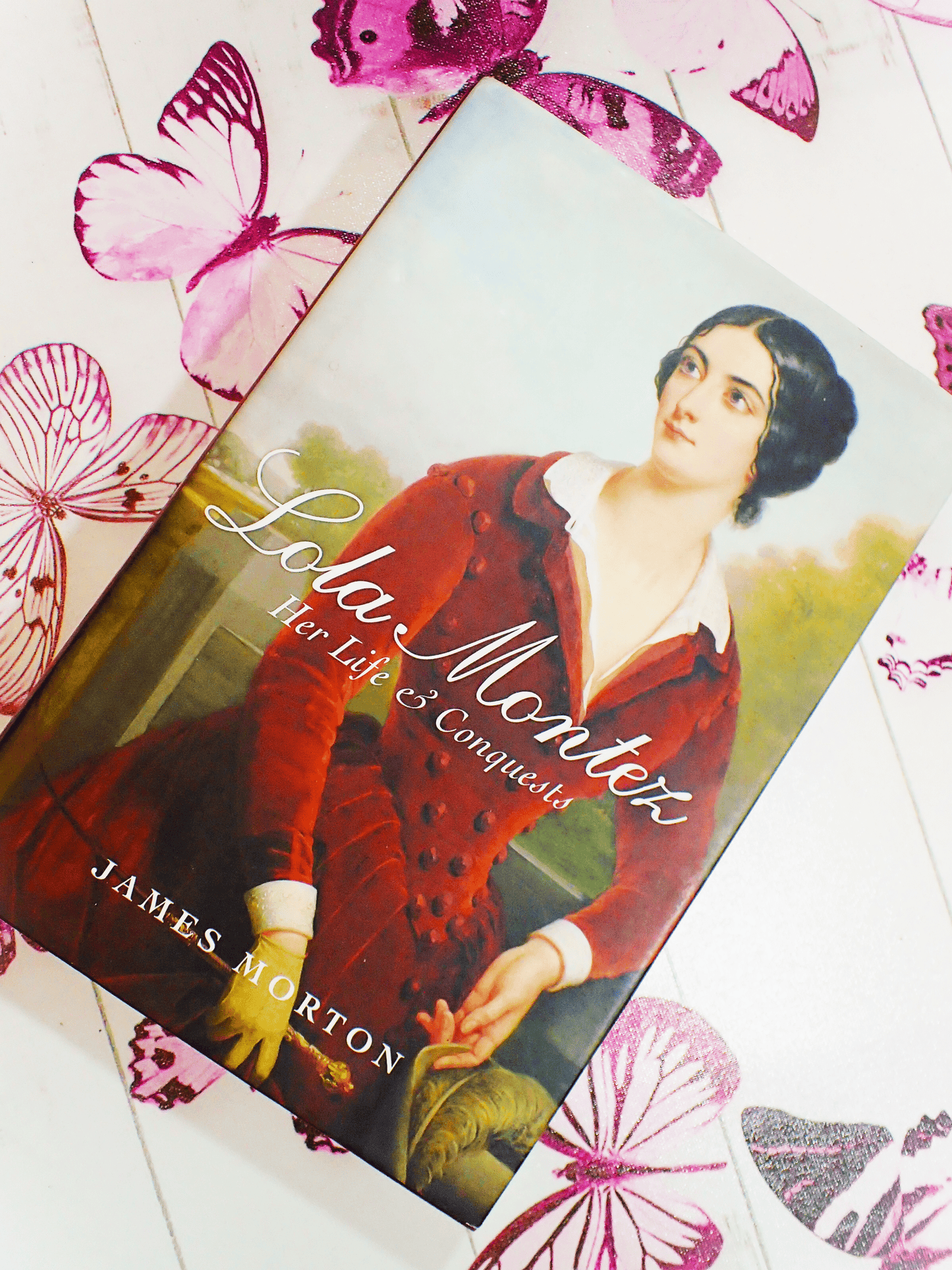 Front cover of Lola Montez Her Life & Conquests by James Morton showing beautiful portrait of Lola Montez in a red velvet gown against a butterfly background.