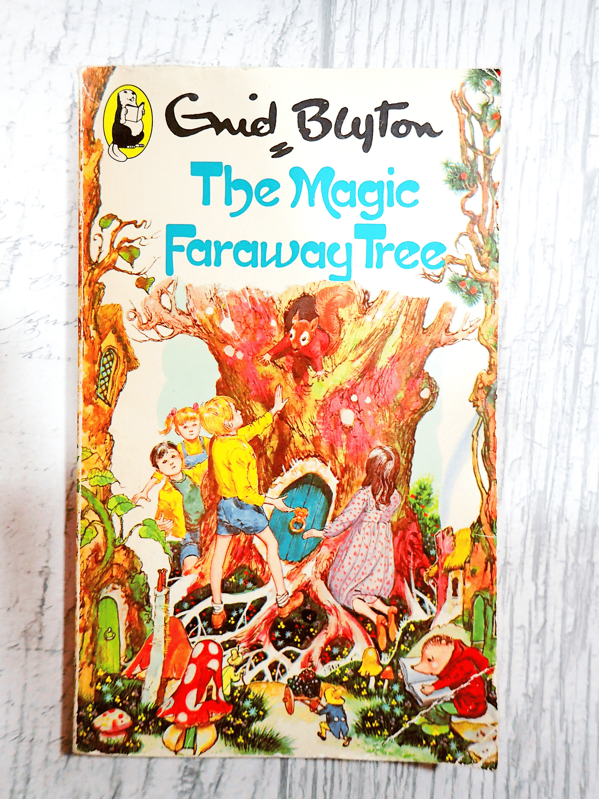 Front cover of The Magic Faraway Tree by Enid Blyton Beaver Paperback Vintage Children's Book 1980's showing children in a magical forest with a squirrel in a tree against a light background. 