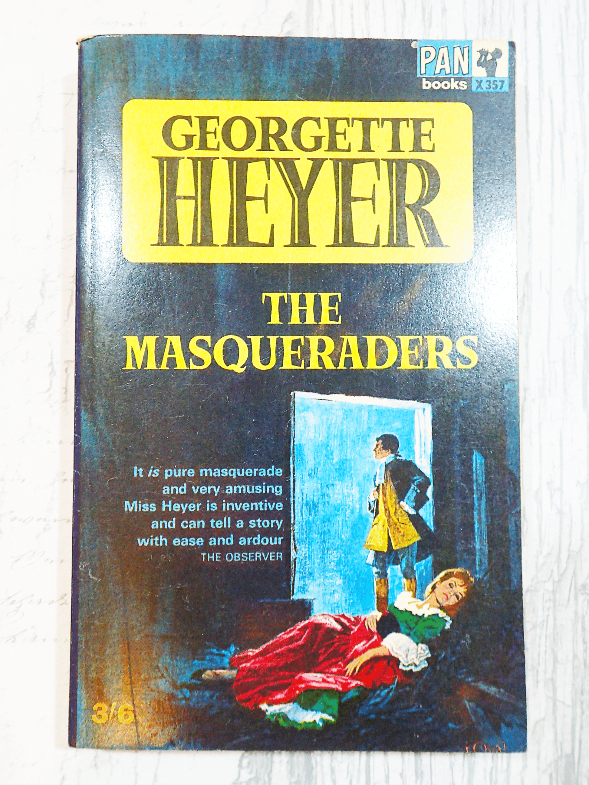 Front cover of vintage Pan paperback book, 'The Masqueraders', by Georgette Heyer showing a man and woman in Georgian costume and the book titles in yellow and black against a light background.