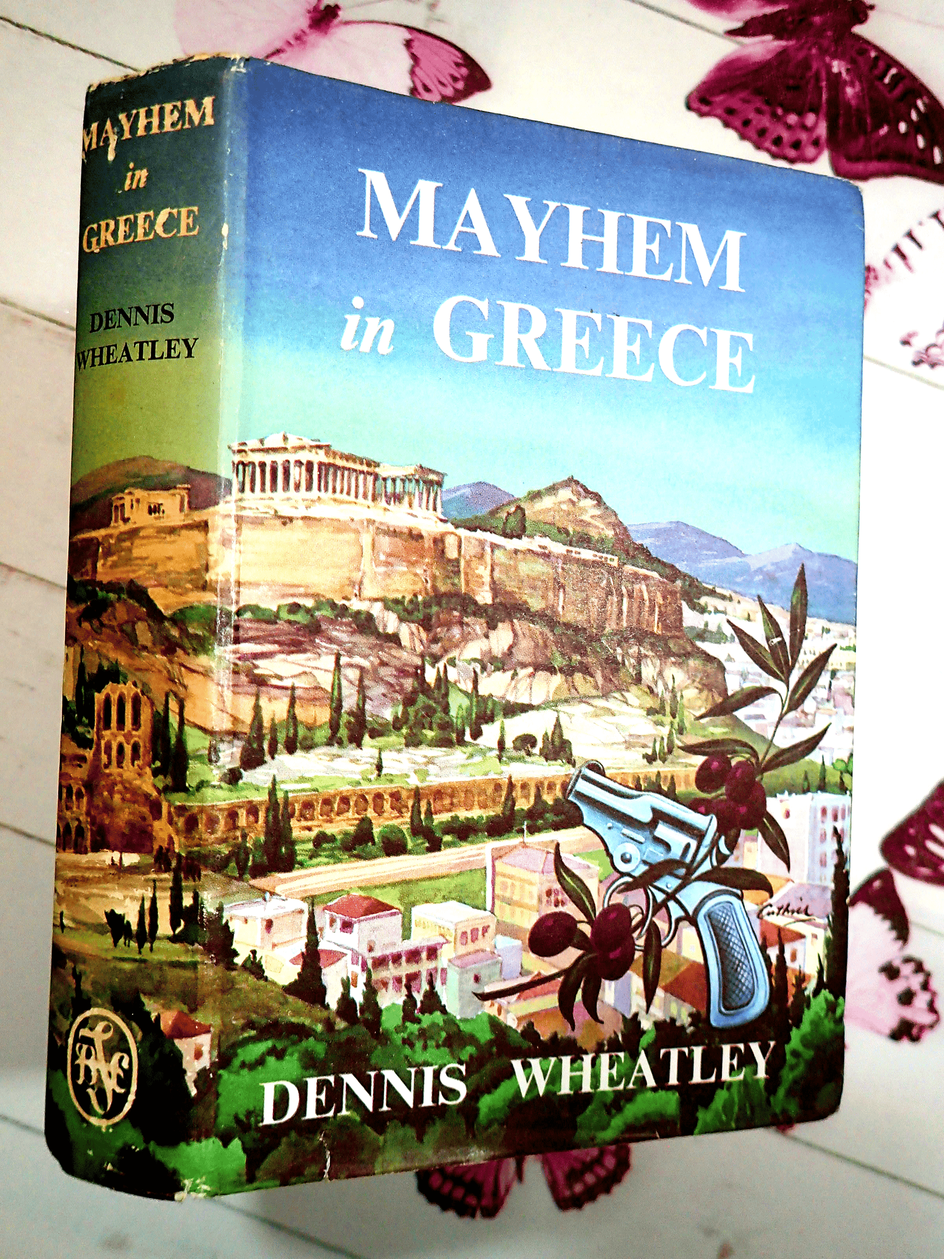 Front cover of Mayhem in Greece Dennis Wheatley Vintage Book BCA showing a Greek landscape with a gun. 