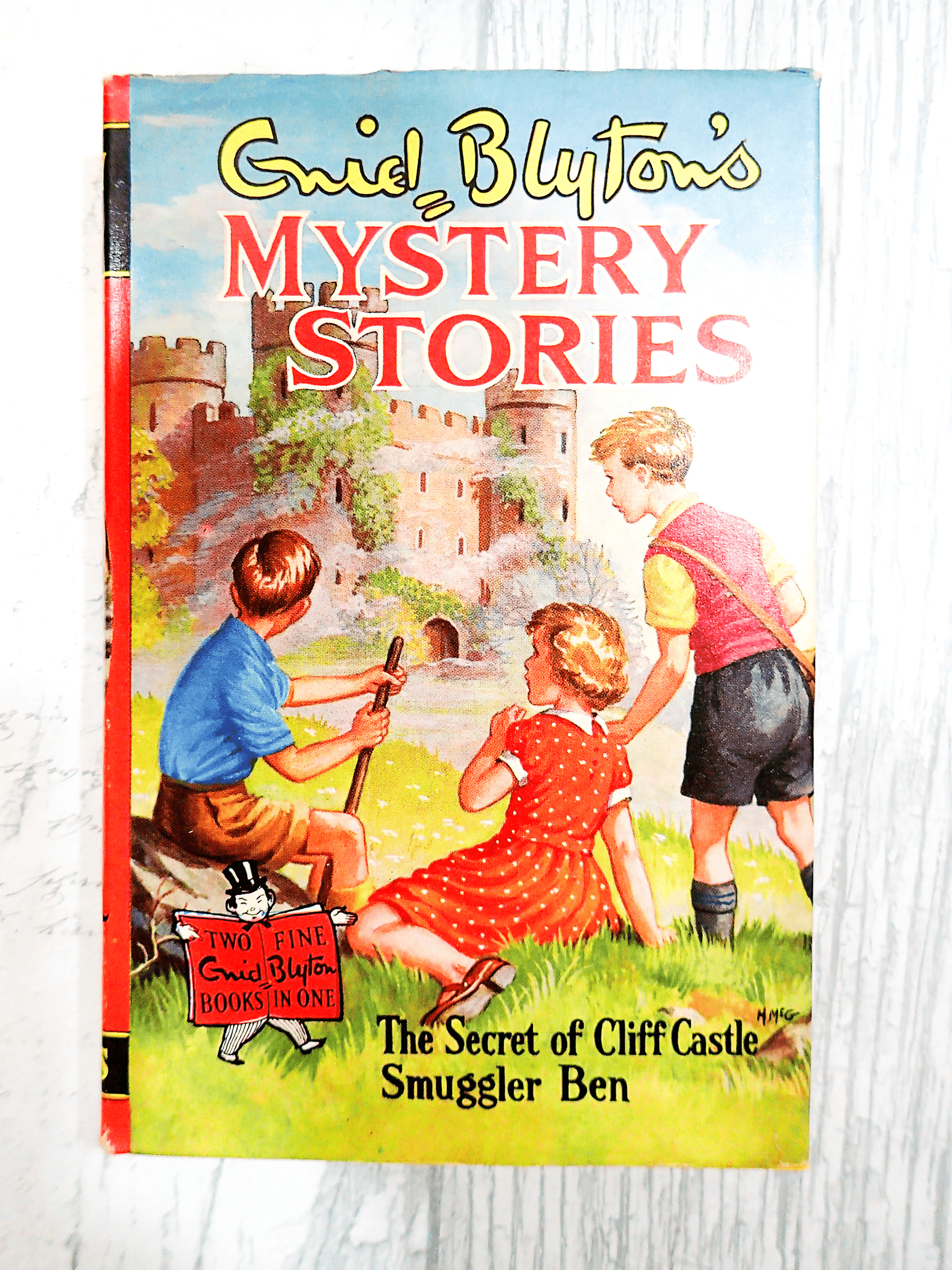 Front cover of Mystery Stories by Enid Blyton Vintage Children's Book Smuggler Ben Secret Cliff Castle 1960's showing three children in front of a castle against a light background. 