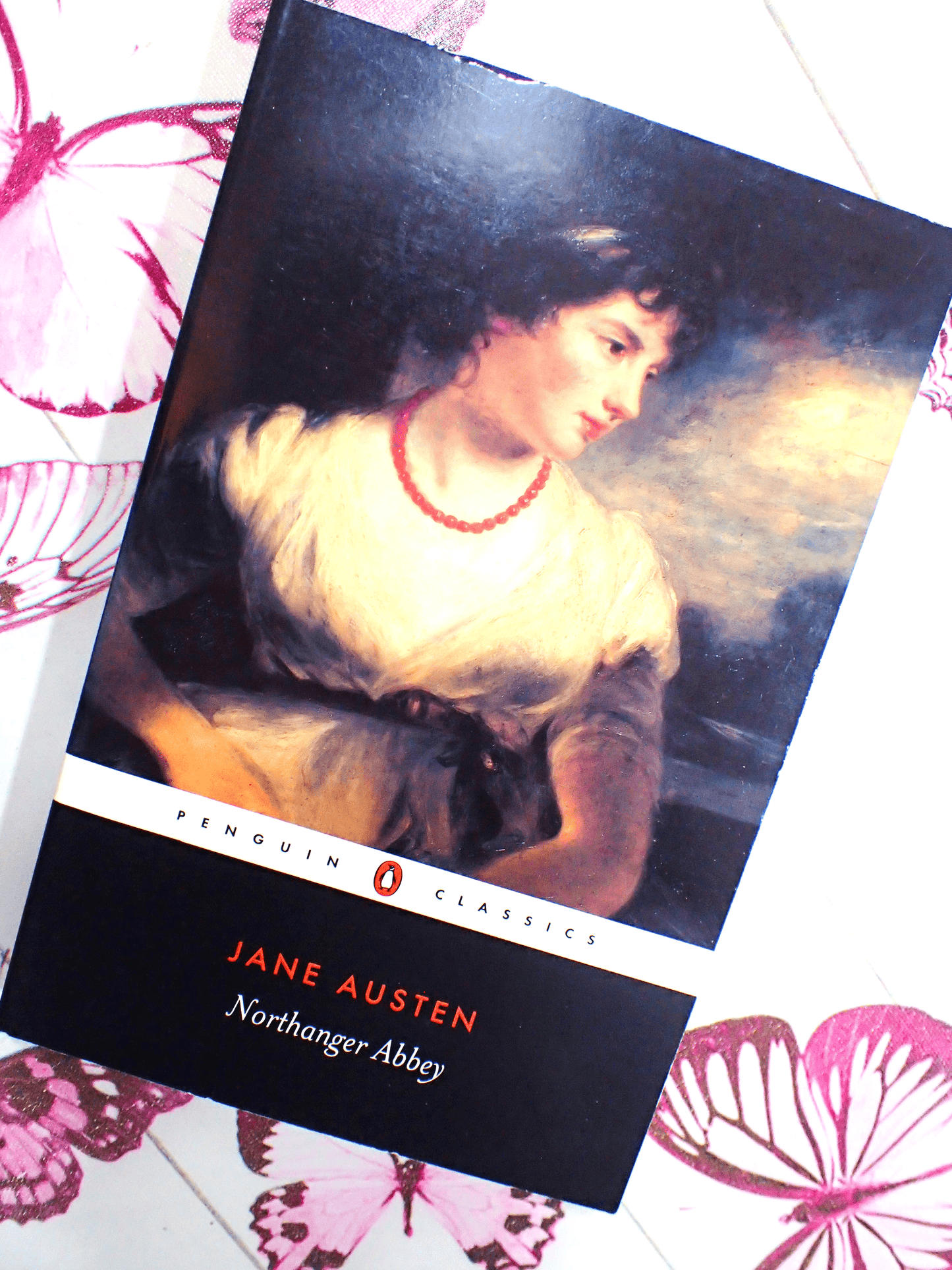 Front cover of Northanger Abbey Jane Austen Puffin Paperback showing a Regency lady wearing a coral necklace against a butterfly background.