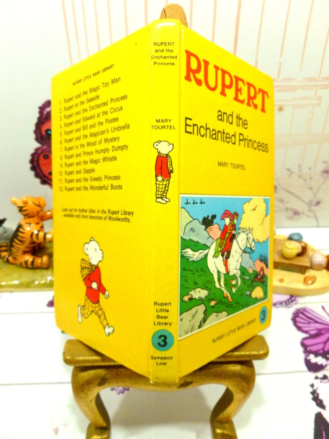 Front cover and spine of yellow book showing Rupert and the Enchanted Princess riding a horse on Mary Tourtel Little Bear Library number 3 1970s Vintage Hardback Rupert Book First Edition and Rupert Bear on the spine.