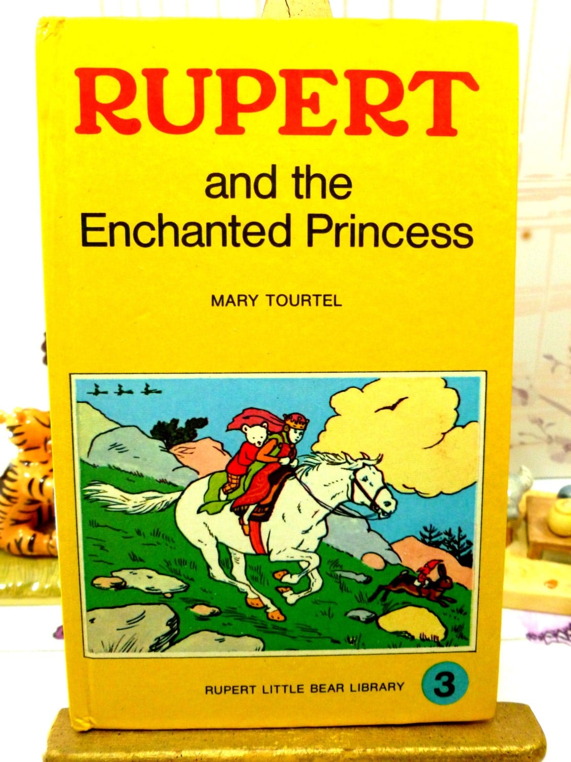 Front cover showing Rupert and the Enchanted Princess riding a horse on Mary Tourtel Little Bear Library number 3 1970s Vintage Hardback Rupert Book First Edition.