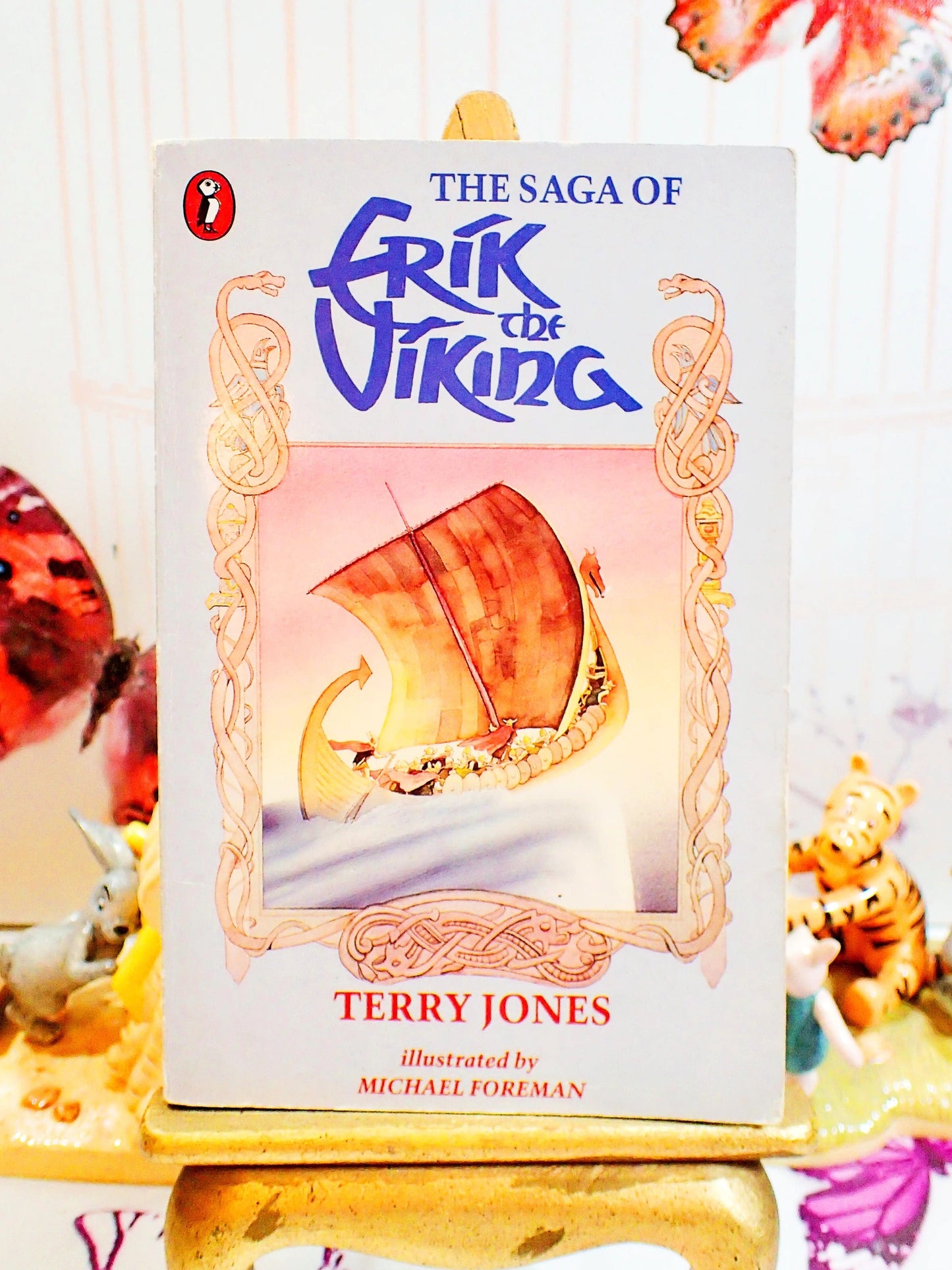 Front cover of The Saga of Erik the Viking by Terry Jones Vintage Puffin Children's Book 1988 showing a Viking Ship sailing against a grey ground with celtic ornamentation. 