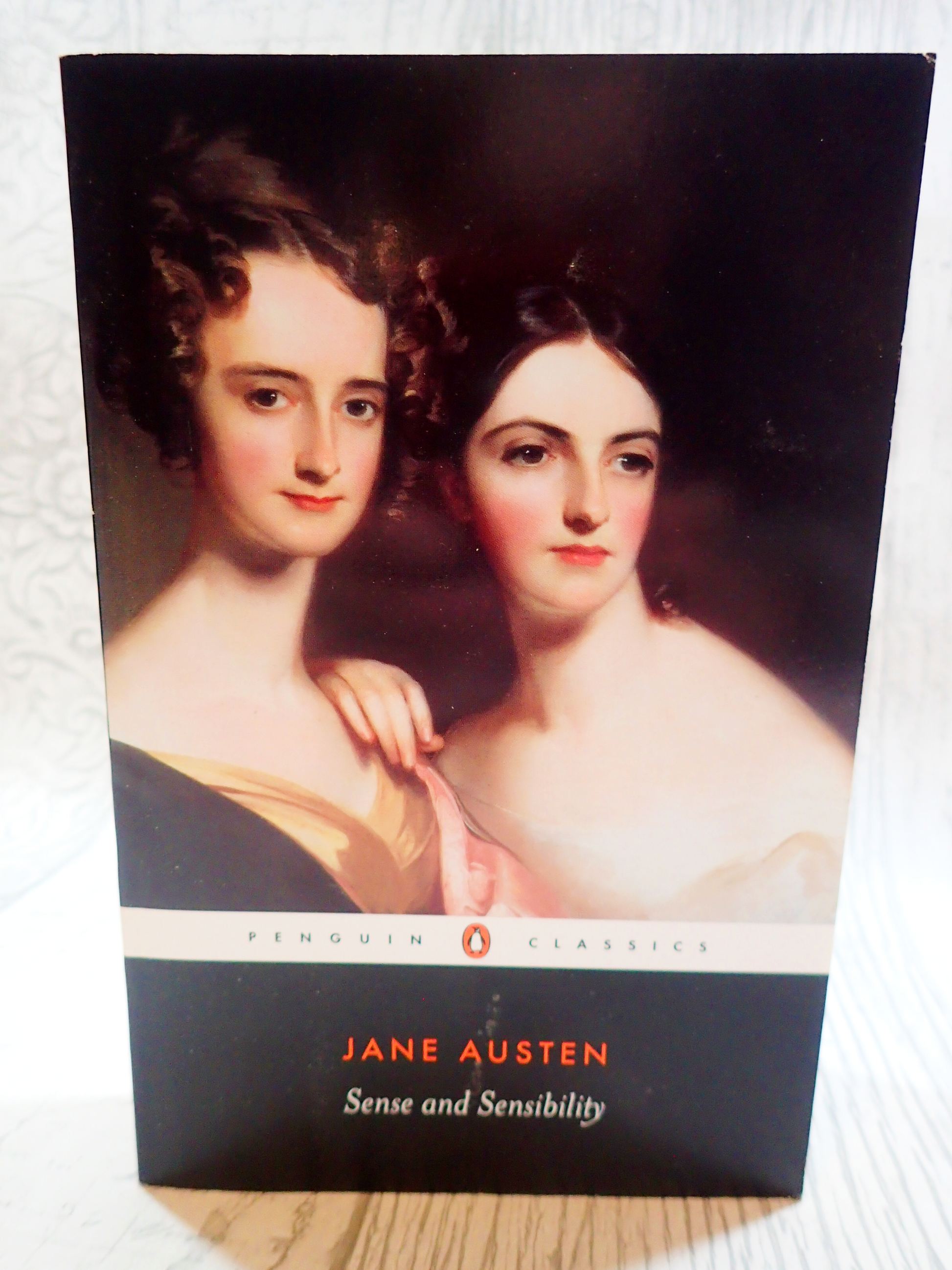 Front cover of paperback book Penguin Classics Sense and Sensibility Jane Austen showing portrait of two Regency ladies against a light background.