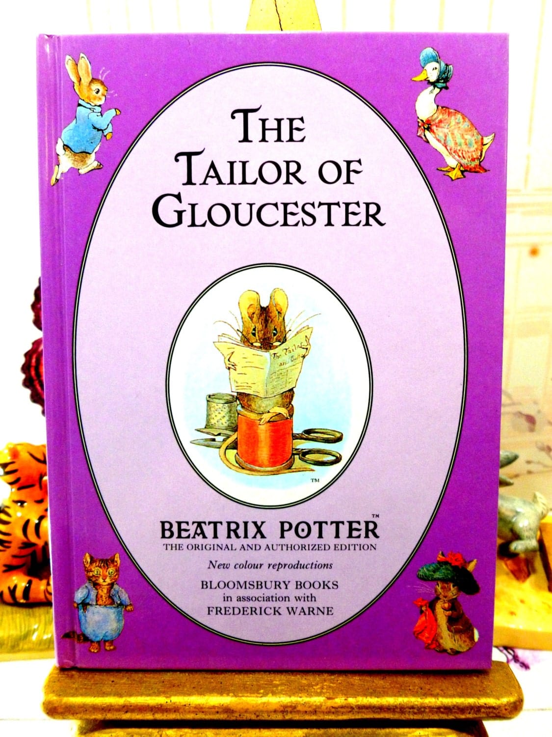 Front cover of The Tailor of Gloucester First Edition Purple Bloomsbury Book 1993 Beatrix Potter Childrens Story showing Beatrix Potter characters on a purple ground.