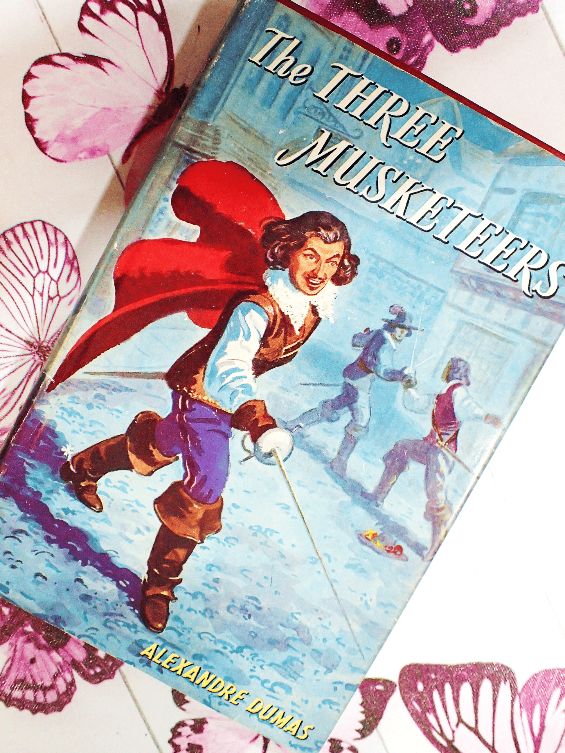 The Front cover of the Three Musketeers by Baroness Orczy vintage book showing a dashing D'artagnan holding a sword. 