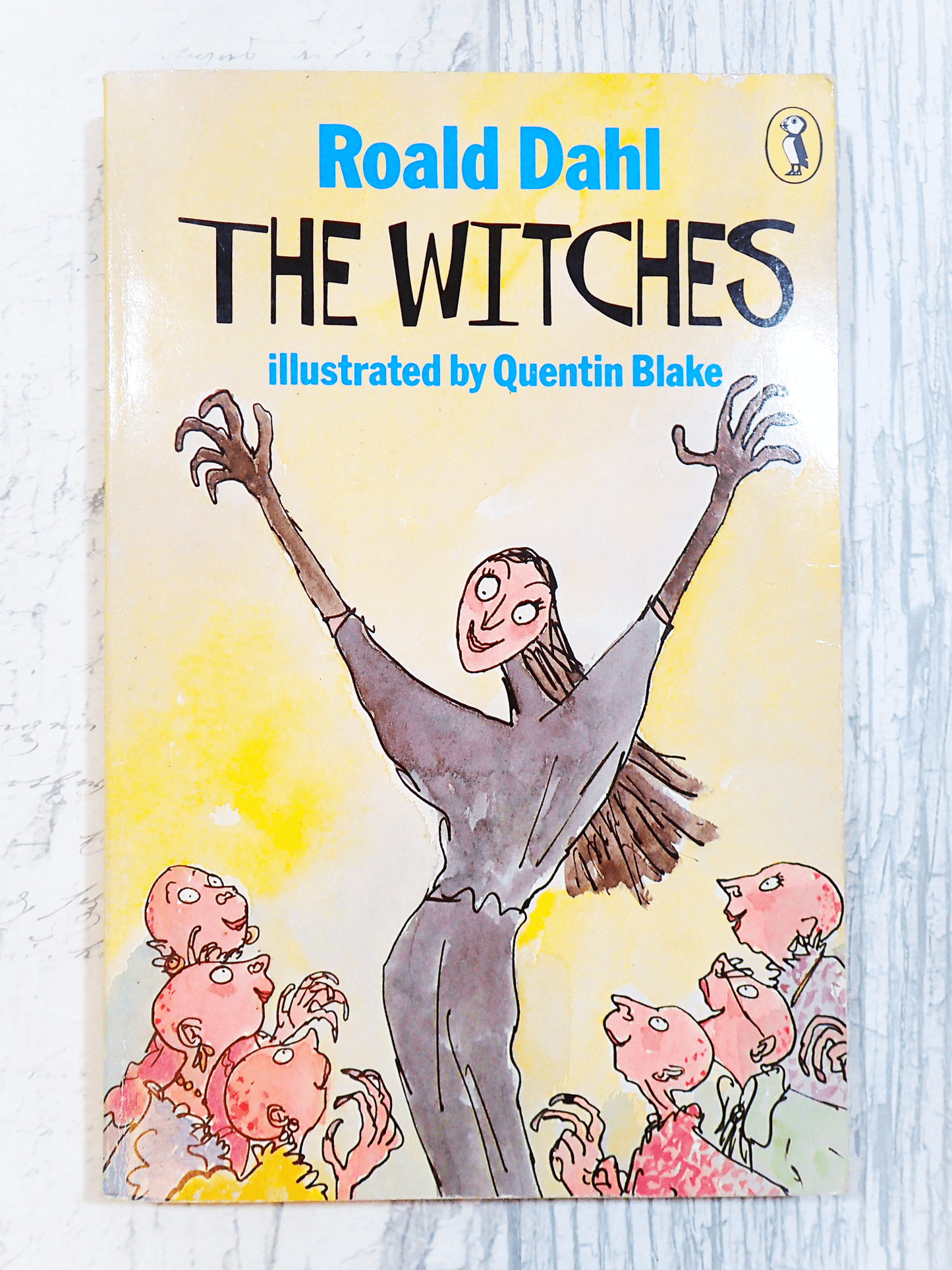 Cover of Vintage Puffin Paperback Roald Dahl 'The Witches' showing a witch with arms raised and titles in blue and black with puffin logo against a light background. 